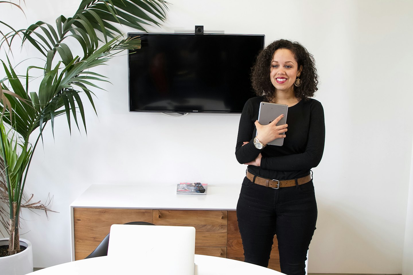 Woman smiling with tablet in modern office meeting room.